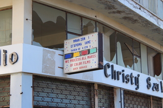 Sign on an abandoned building saying: we process all makes of color films